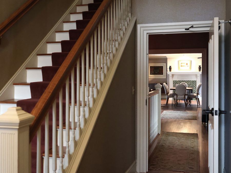 The front staircase, with white balusters and a dark timber handrail, looking through to the rooms beyond
